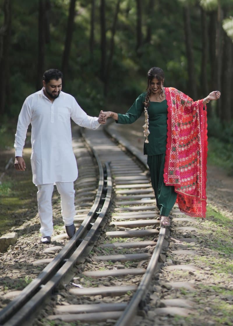 Samriti and Sarthak holding hands along a railway track